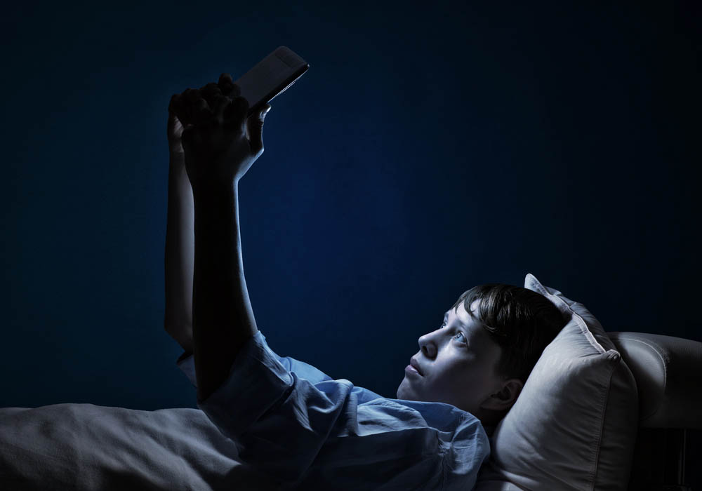 Child in bed at night with phone