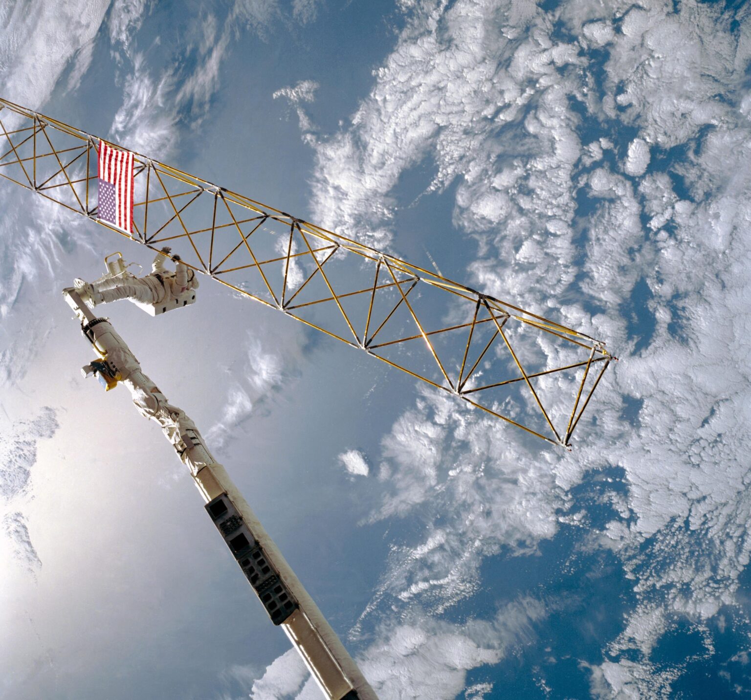 Astronaut Sherwood C. Spring checking joints on the ACCESS structure. The purpose of ACCESS was to study construction techniques in space.