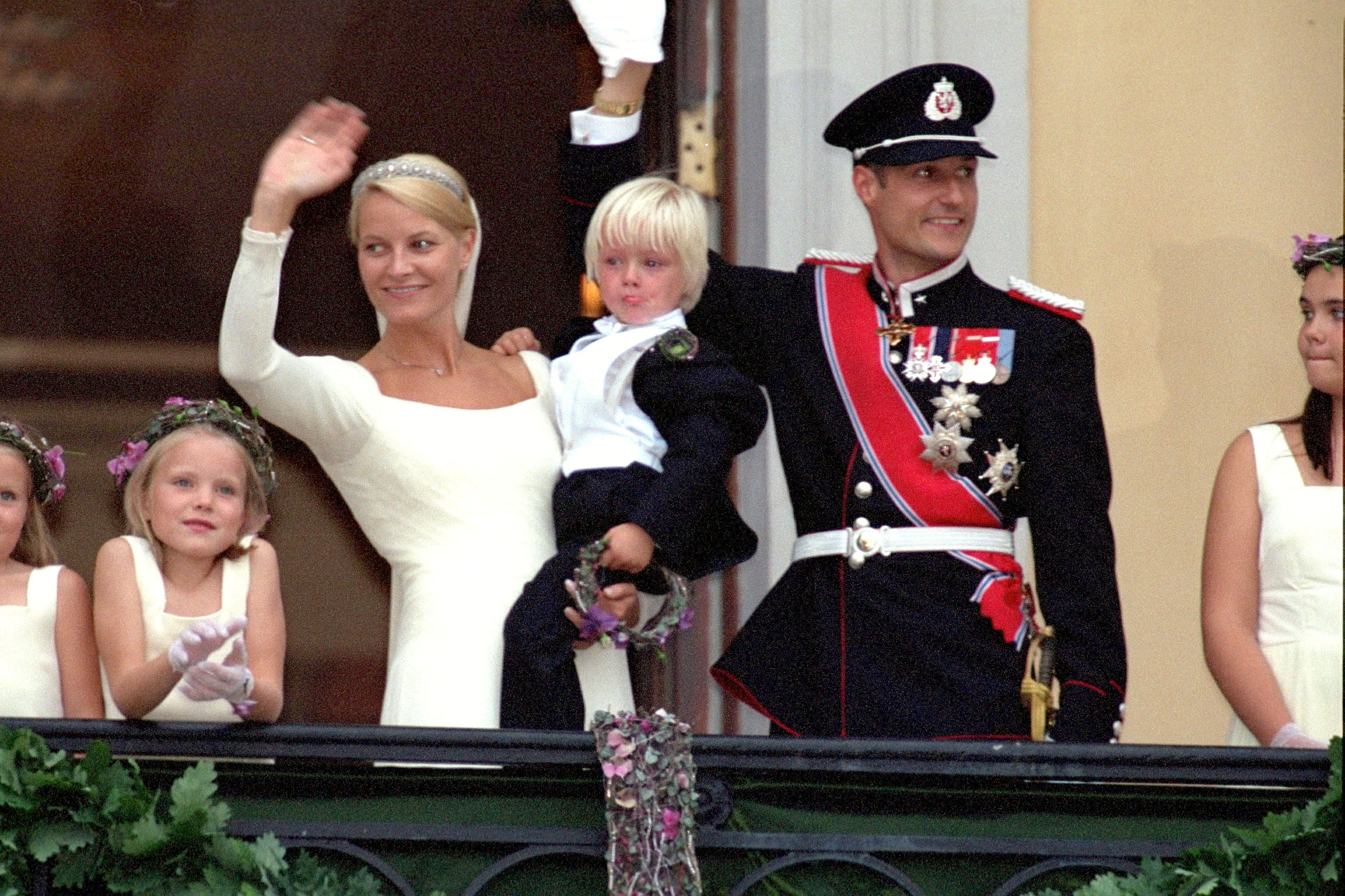 Crown Princess Mette-Marit holding her son Marius Borg Hoiby, with Crown Prince Haakon Magnus on the royal palace balcony.
