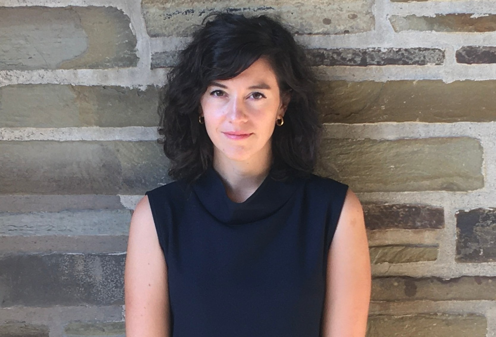 Sophie Pinkham, author of "The Oak and the Larch: A Forest History of Russia and its Empires", standing in front of a stone wall.