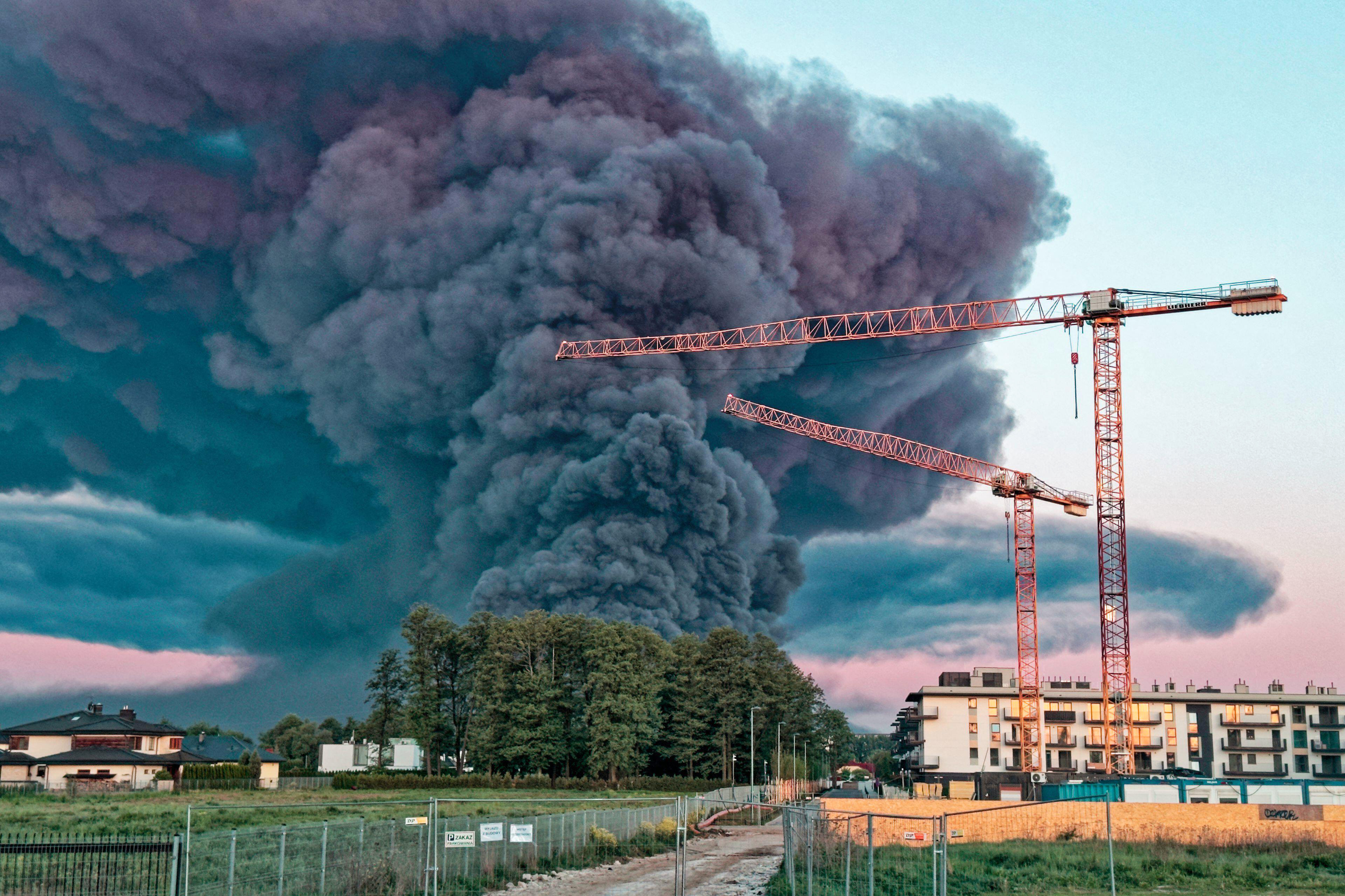 Thick black smoke rising from the Marywilska 44 fire behind cranes at a construction site in Bialoleka.