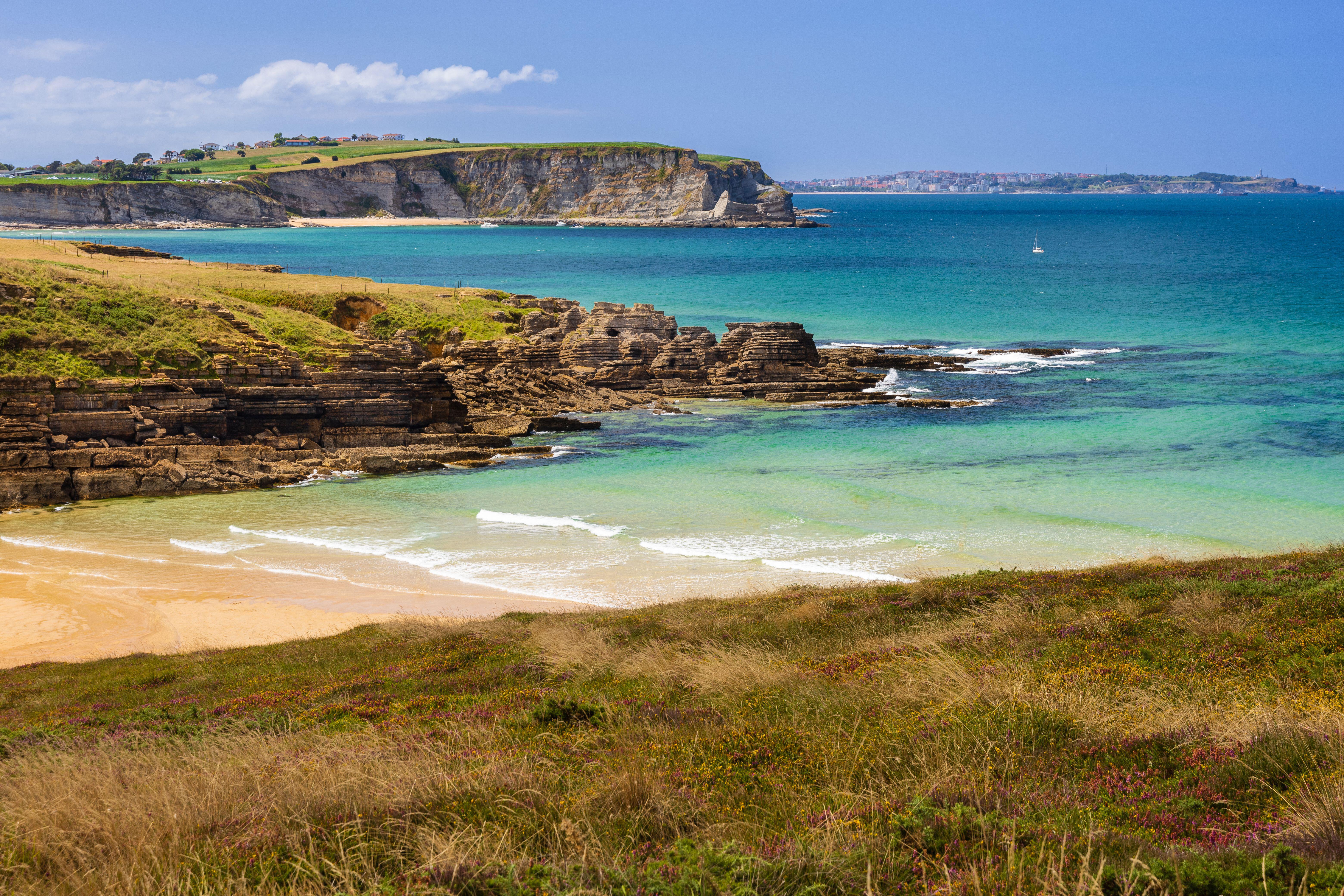 Playa de Galizano (San Miguel or La Canal beach) with sandy shores, scattered rocks, and soft cliffs.