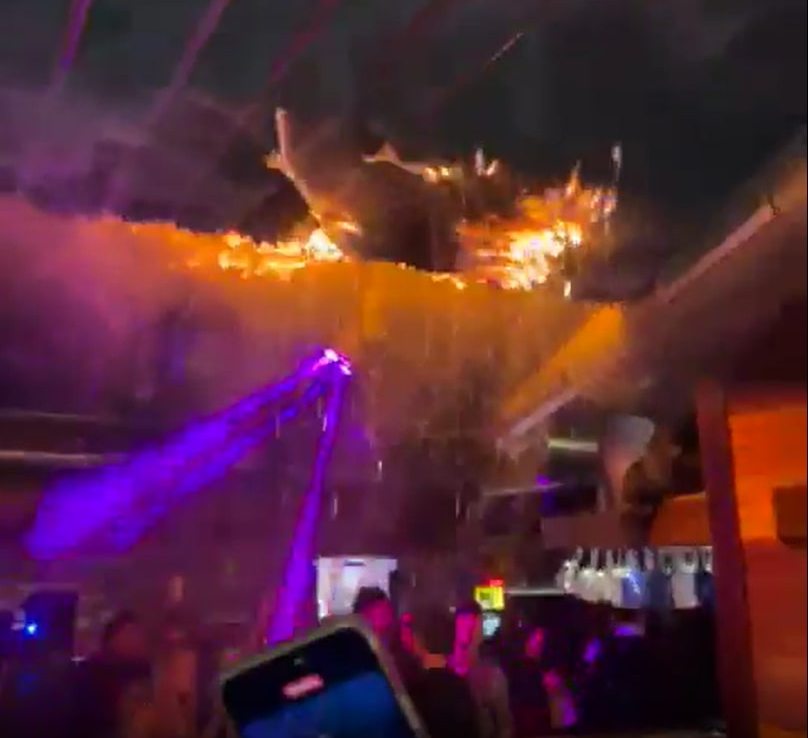 Fire spreading across a ceiling in a crowded bar.