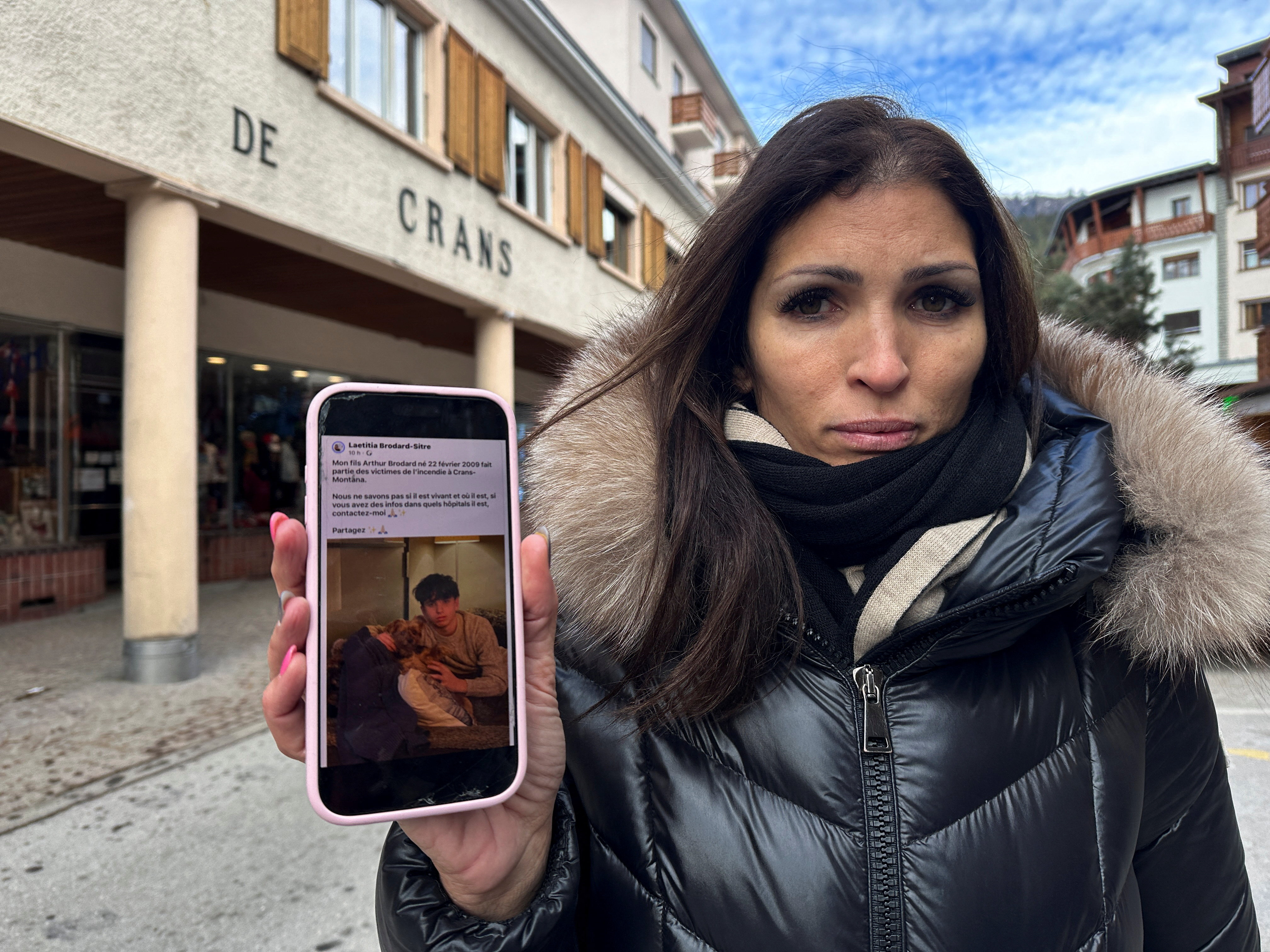 Laetitia Brodard-Sitre holds a phone displaying her social media post about her missing son, Arthur, who disappeared after a fire at "Le Constellation" bar.