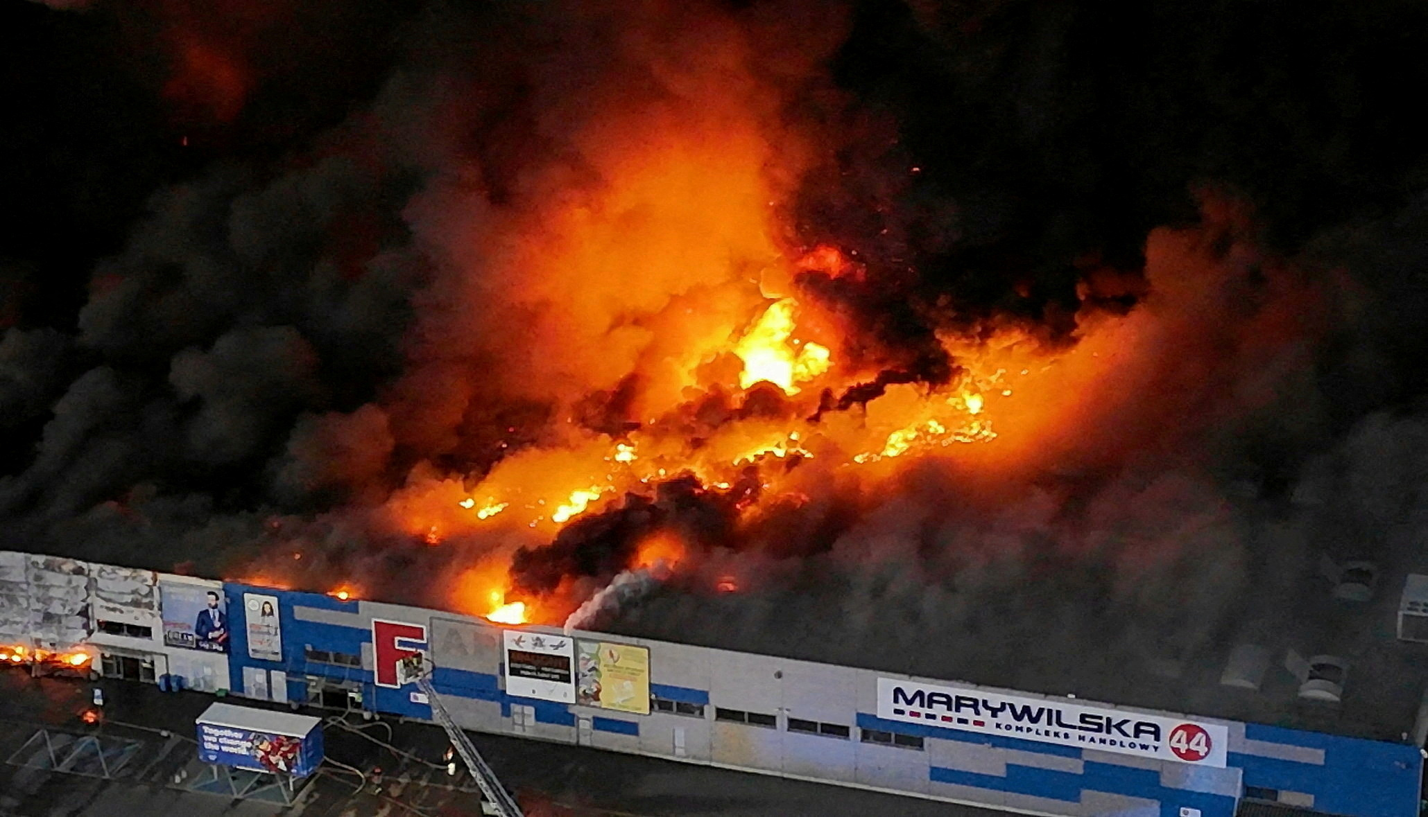 Drone view of the Marywilska 44 shopping center burning with massive flames and smoke in Warsaw, Poland.