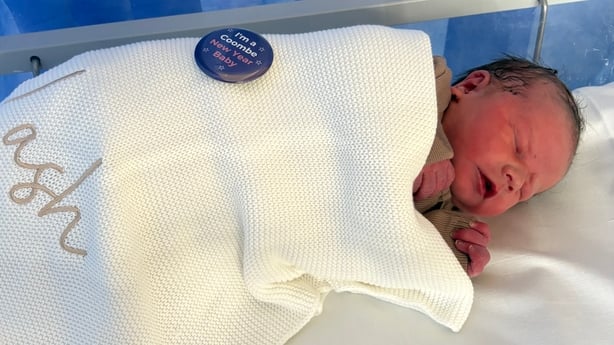 a newborn baby covered in a blanked with the name 'Kash' embroidered on it