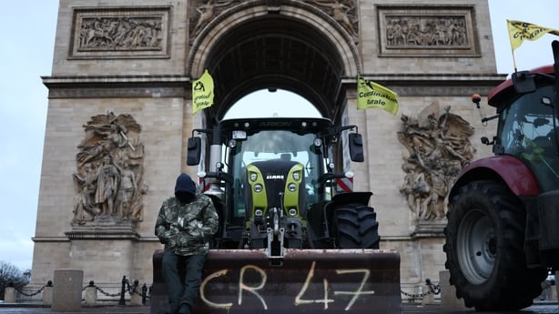 a man leans against a front loader tractor 