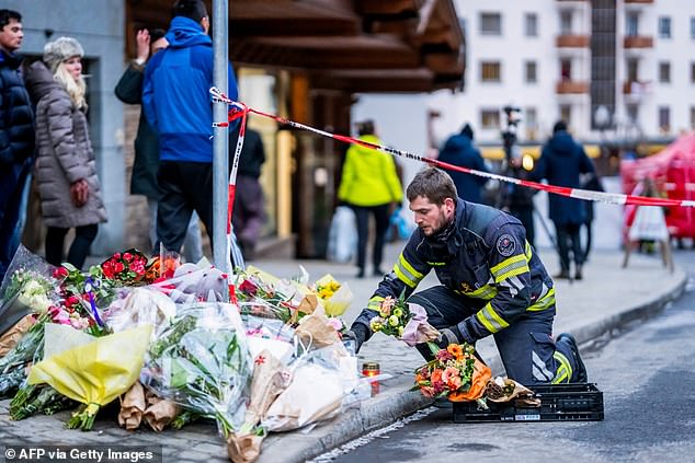 A firefighter displays flowers at a makeshift memorial near the site of a fire that ripped through the bar during New Year's Eve celebrations