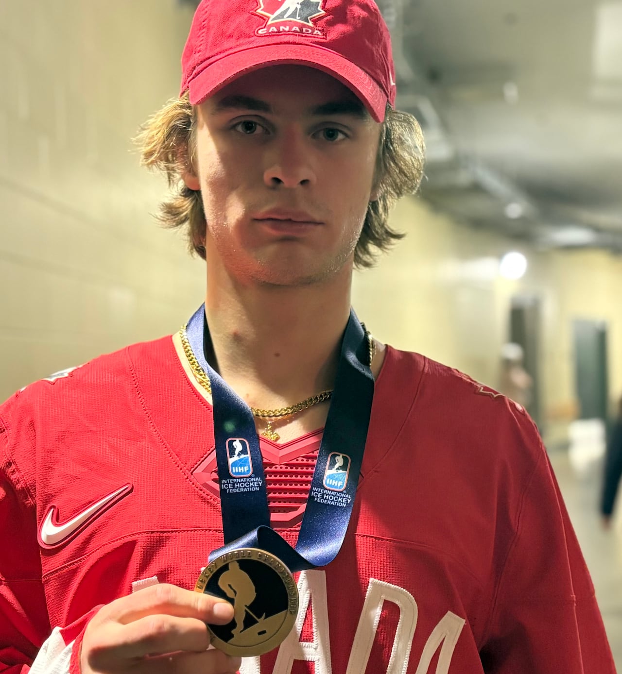 A young man in a Canada hockey jersey wearing a bronze medal around his neck.
