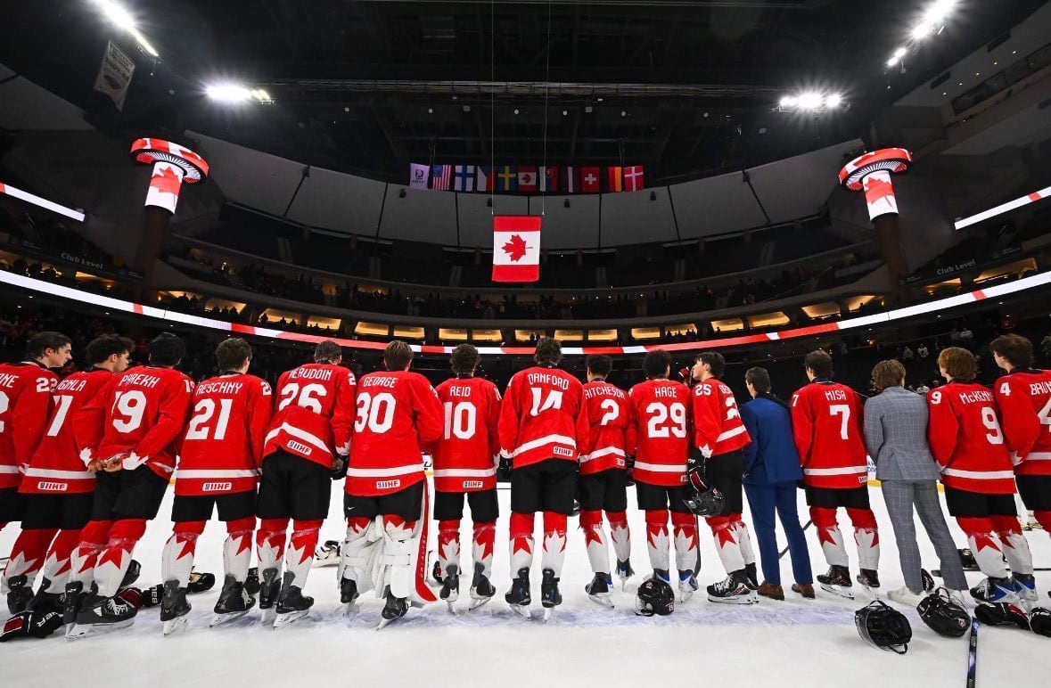 A hockey team in red jerseys is seen from the back, lined up on the ice.
