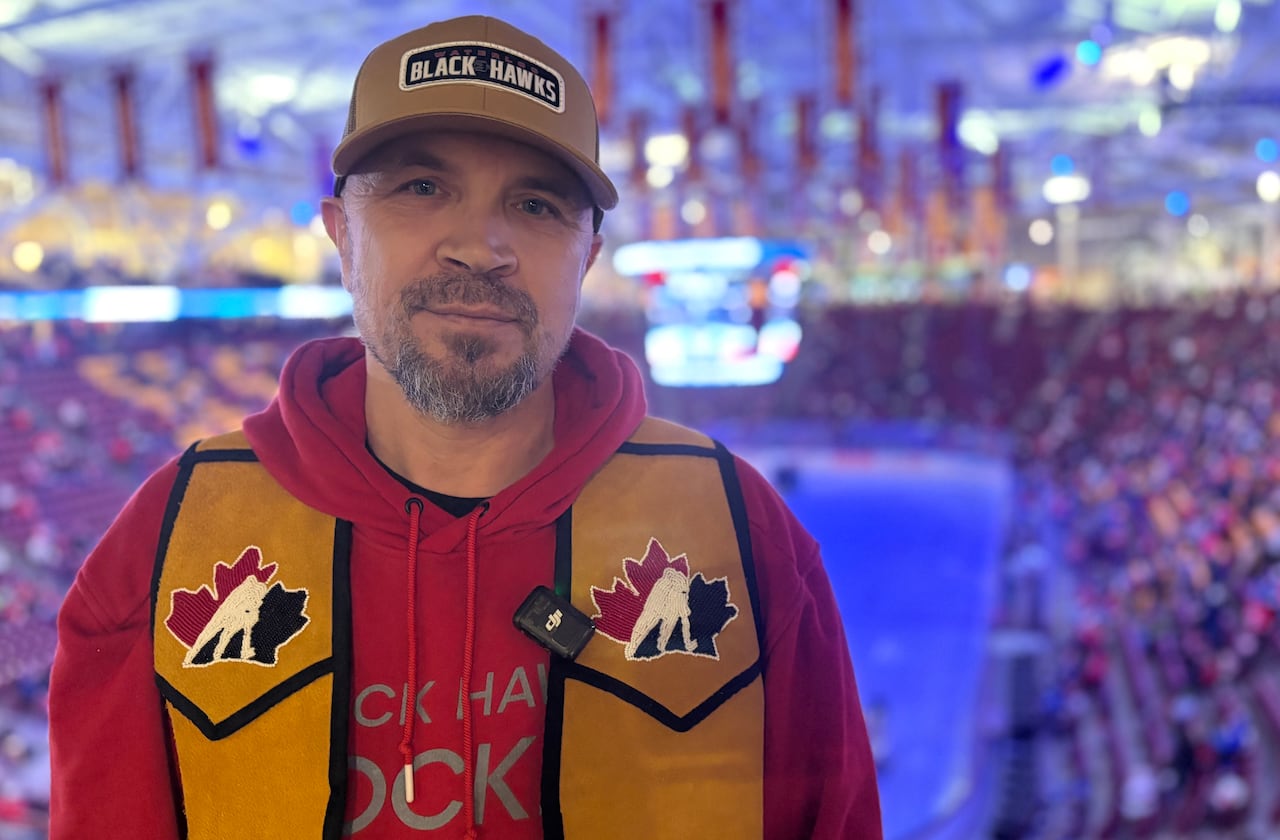 A man stands posing inside a hockey arena.