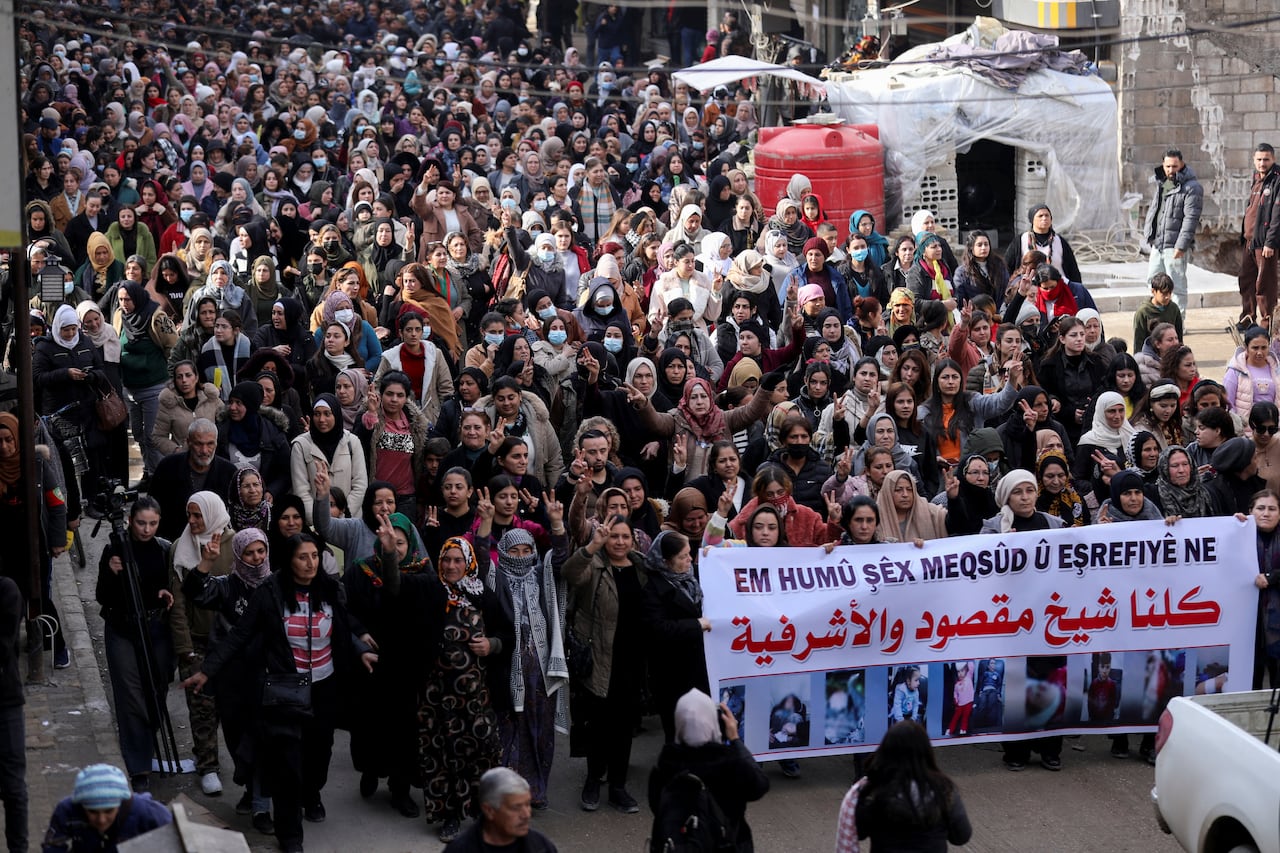 Dozens of people seen at a demonstration with many putting up the peace sign with their hands.
