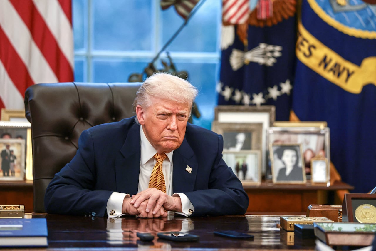 A man frowns while sitting at an ornate desk