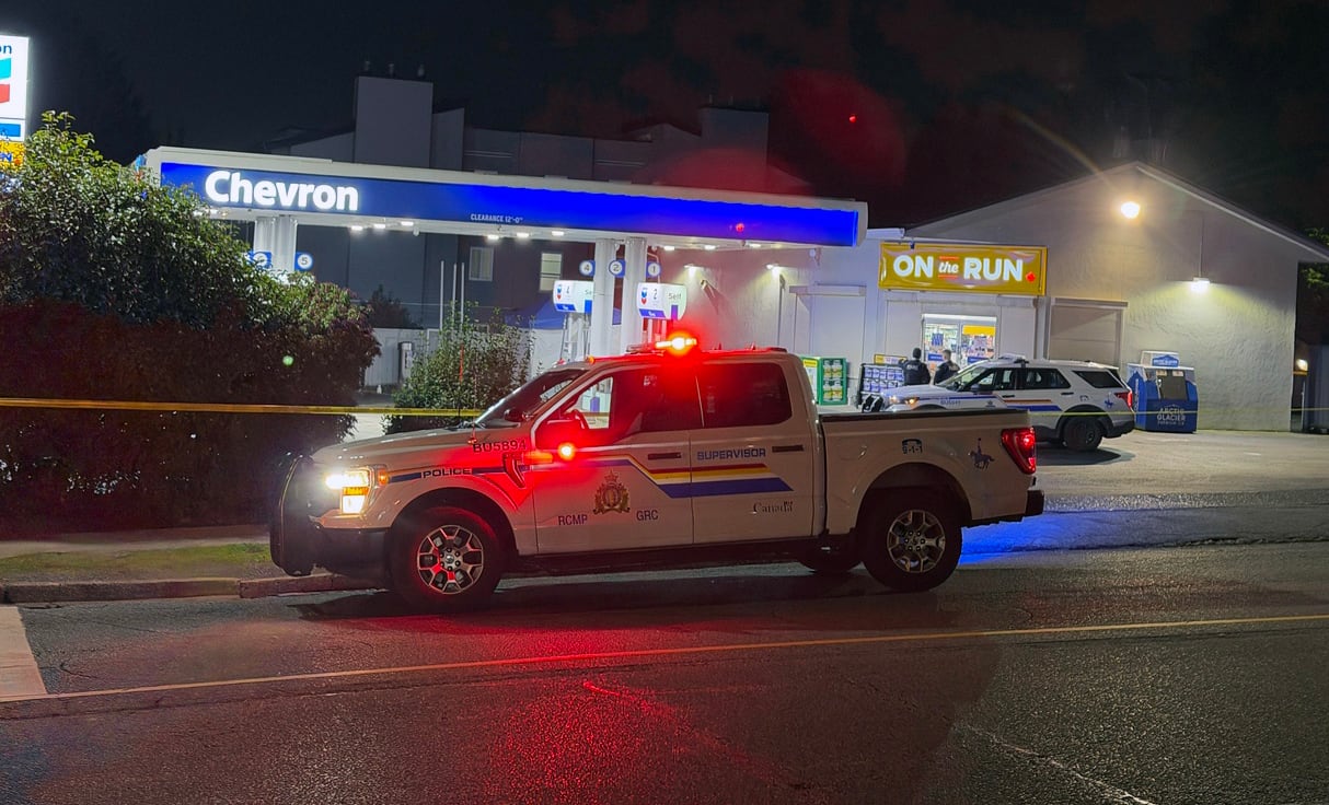 A police car with flashing lights at a gas station.