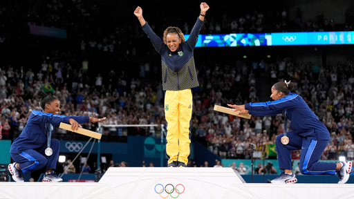 FILE - Silver medalist Simone Biles, of the United States, left, and bronze medalist Jordan Chiles, of the United States, right, bow to gold medalist Rebeca Andrade, of Brazil, during the medal ceremony for the women