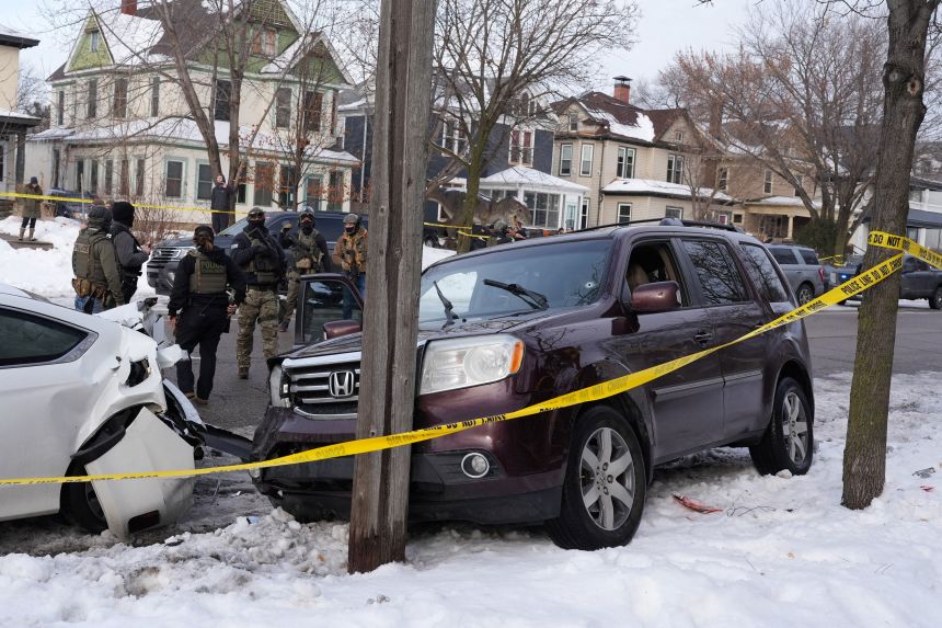 Federal agents gather next to a vehicle with a bullet hole in the windshield after its driver was shot by a US immigration agent in Minneapolis on January 7.