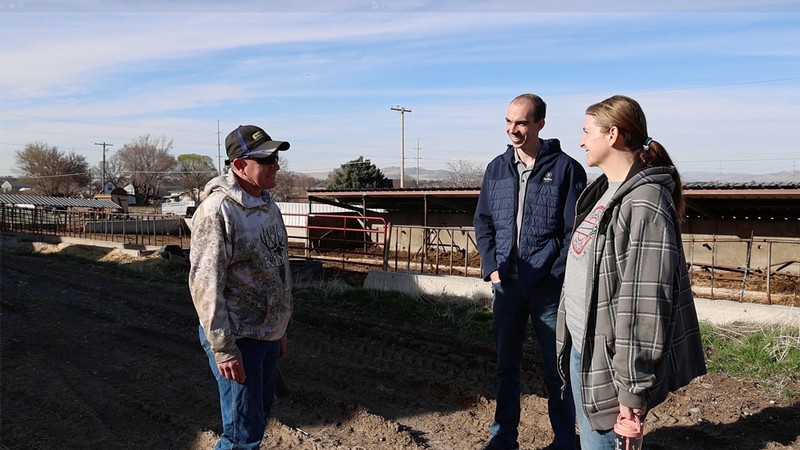 Three people speaking on a farm in rural Utah.
