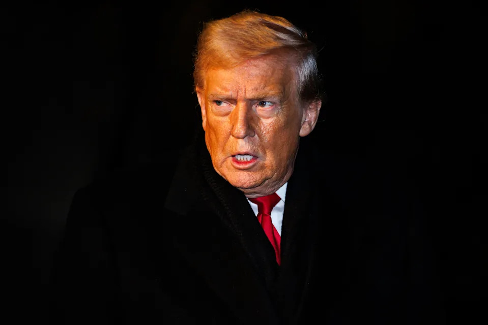 A man in a formal black coat and red tie looks intently to the side, appearing deep in thought