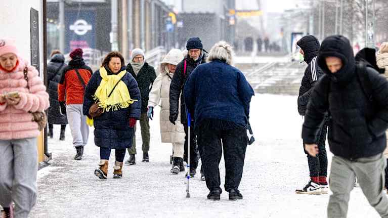 People walking on a snowy city pedestrian area during the day.