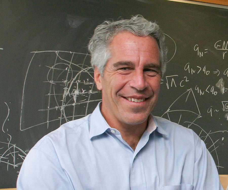 A man standing in front of a chalkboard that is covered in equations.