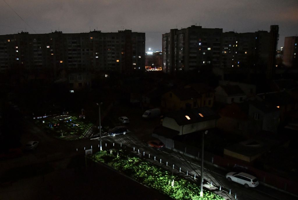 A dark street in Lviv, Ukraine, with some scattered lights in buildings and on the ground, indicating a power cut-off.