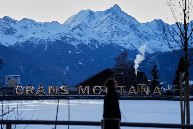 A woman walks in the early morning in Crans-Montana, Swiss Alps, Switzerland, Saturday, January 3, 2026.