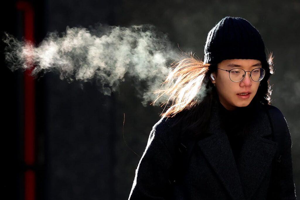 A person walks in downtown Boston during a frigid December day. To understand how a warming climate can unleash bitter cold, some experts are looking to the winds that circle the Arctic.