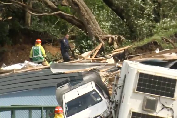 In this image from a video, a police officer with a dog searches for people near the site of a landslide at the base of Mount Maunganui on New Zealand’s North Island.