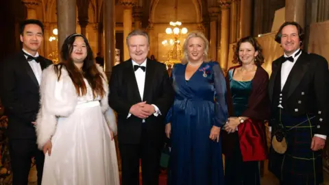 Vienna Tourist Board/Martin Morscher Three men and three women dressed in ball gowns and black-tie attire at the Vienna Ball of Sciences. The Mayor of Vienna Dr Michael Ludwig and the British Ambassador to Austria stand in the middle. 