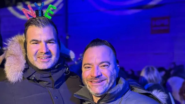 Two friends pictured, one wearing a NYE hat