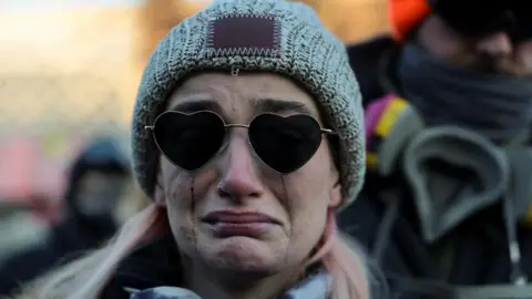 Reuters Mascara runs down the face of a woman wearing heart shaped glasses and a hat