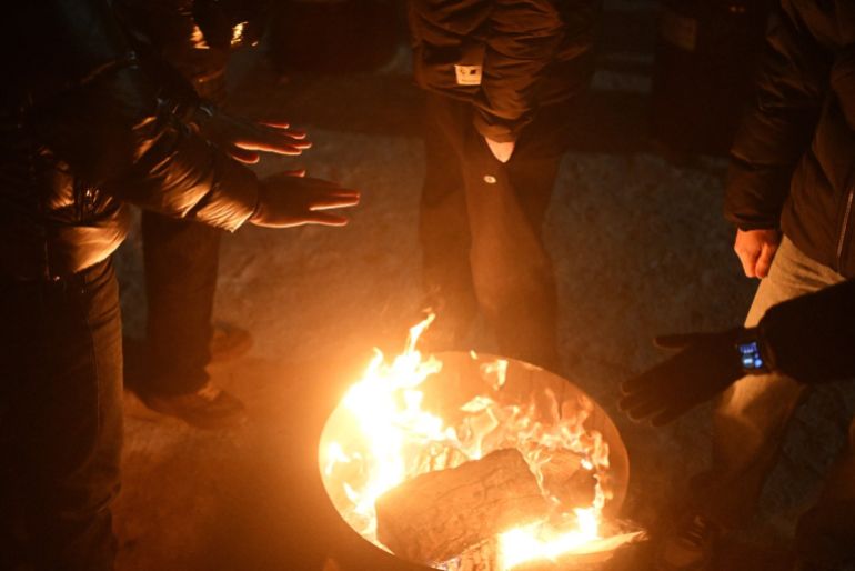Local residents gather around a bonfire during an outdoor party to keep warm as many apartments remain without heating in Kyiv on January 18, 2026, amid the Russian invasion of Ukraine. Russian attacks have left Ukraine's energy grid teetering on the brink of collapse and have disrupted power and water supplies to millions over recent weeks