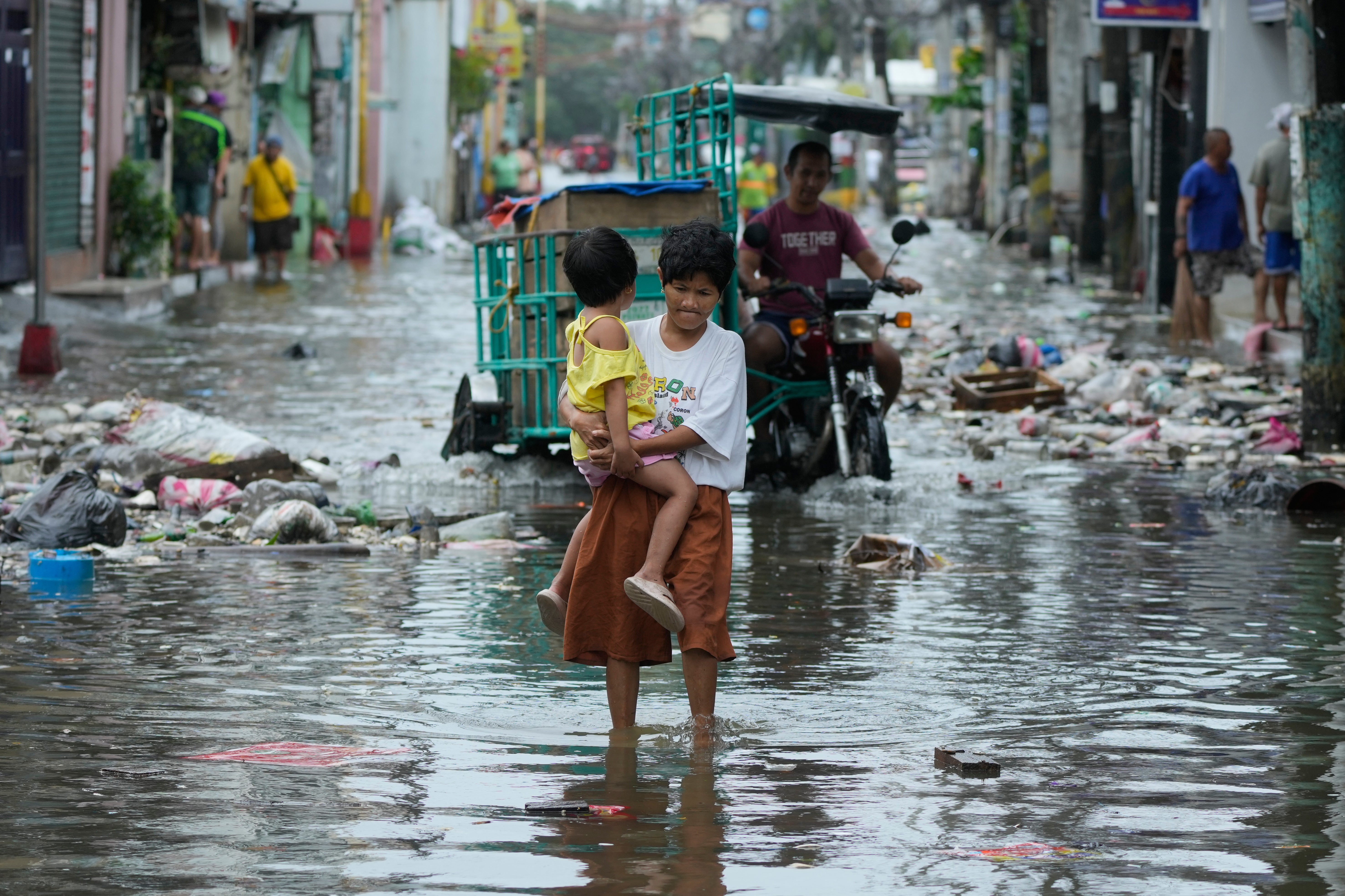 A woman and child crosses a flooded street due to Typhoon Fung-wong in Navotas, Philippines last November
