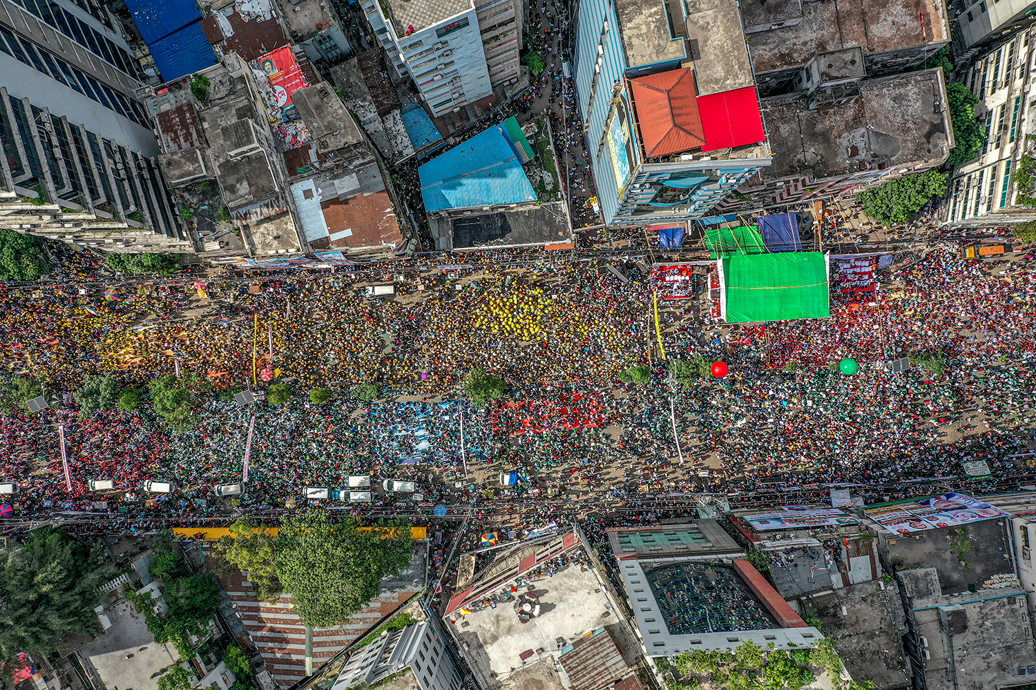 An aerial view captures an enormous political rally or demonstration filling a major urban street.
