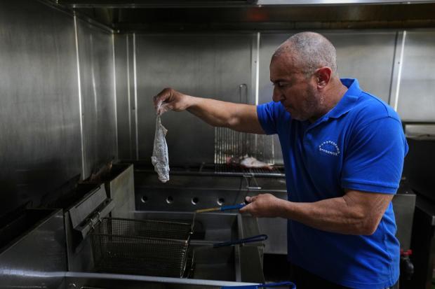 Stefanos Mentonis, owner of Stefanos restaurant, cooks lionfish in Larnaca, Cyprus