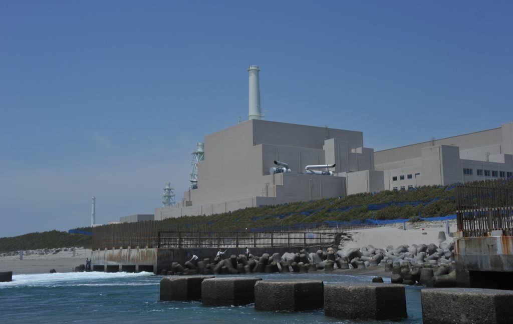 Image of a large, blocky concrete building located up a small slope from the ocean.