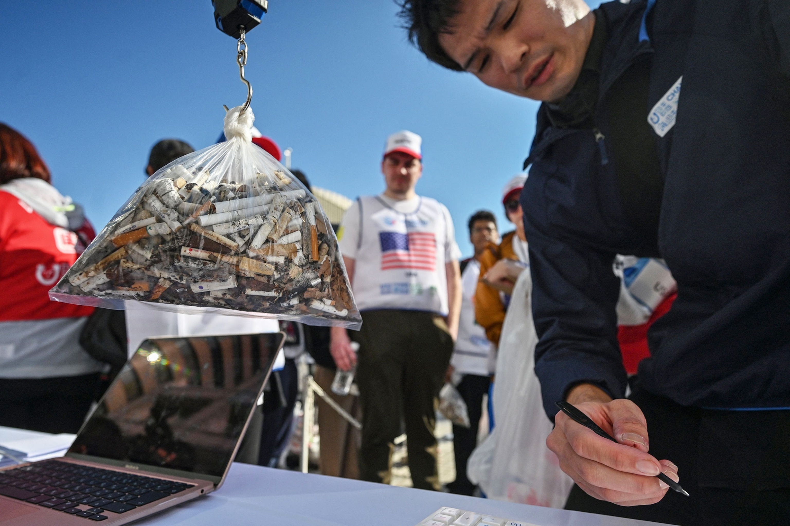 Members of the US watch as the cigarette butts they collected are weighed after the second round of the final, in which teams pick up as much rubbish as possible in a set amount of time, at the United Nations University in Shibuya ward.