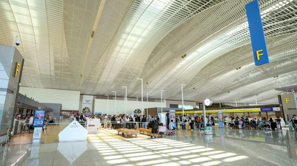 Incheon launches automated remote baggage screening system between South Korea and USA Check-in hall at Incheon airport, with a high ceiling with multiple large windows, check-in counters, and passengers standing in short queues.