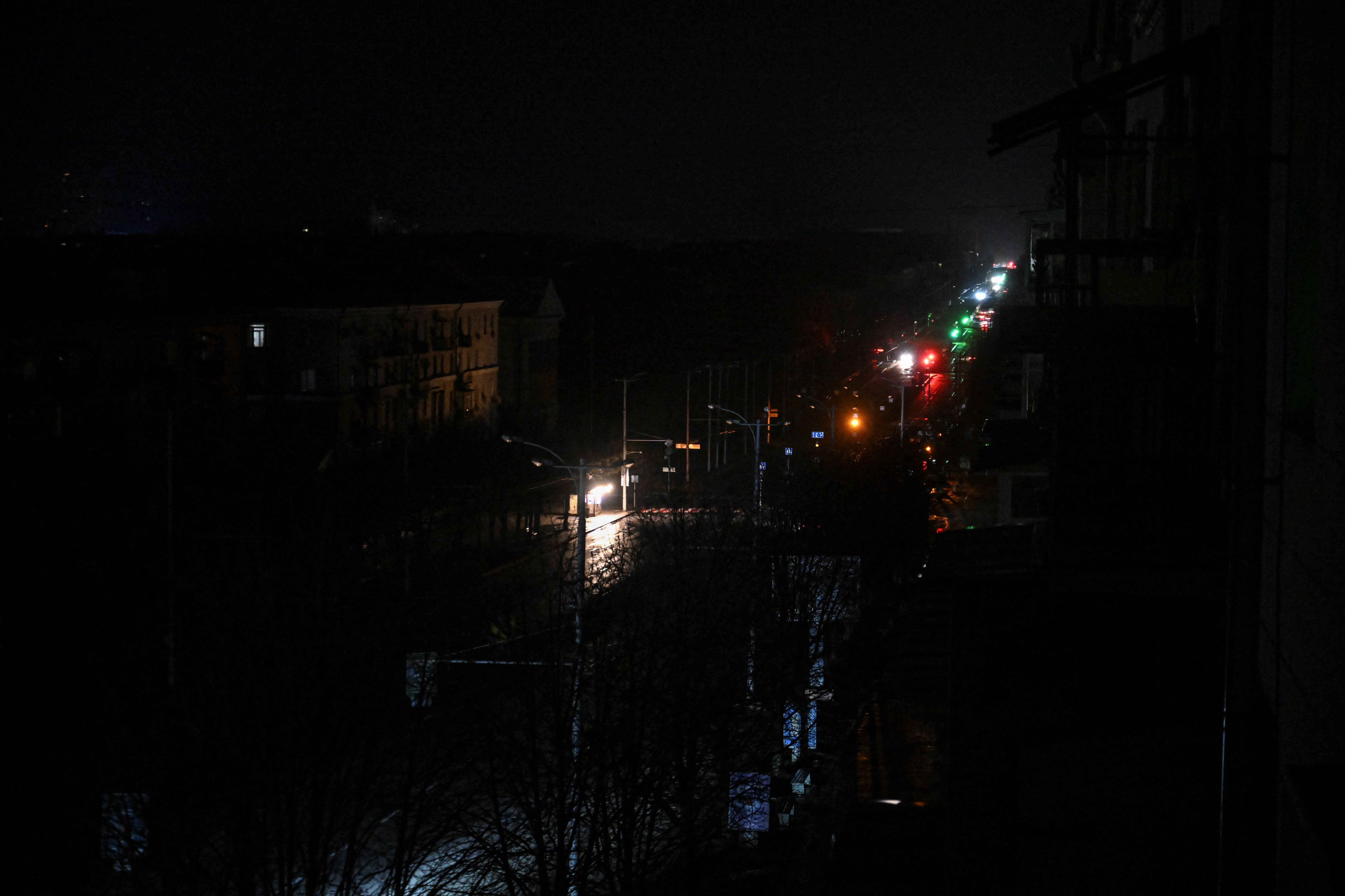 Cars move along a dark street during a power blackout after critical civil infrastructure was hit by today's Russian drone strikes in Zaporizhzhia
