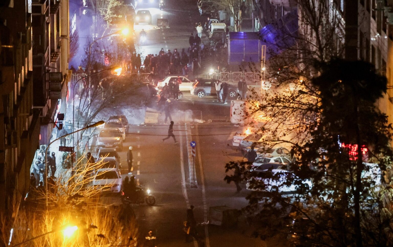A demonstrator darts across a street in Tehran. Protests about the Iranian economy began in late December