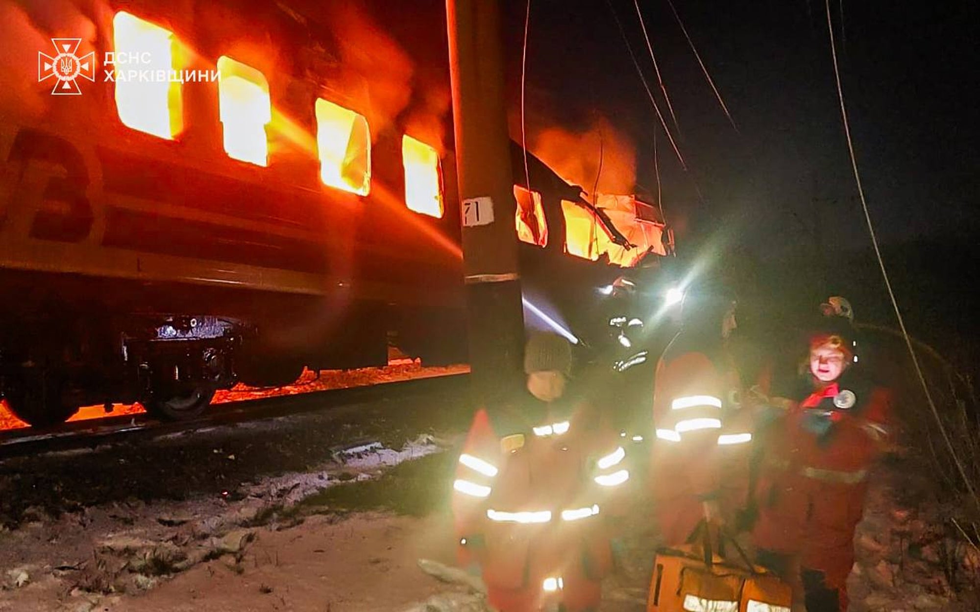 Train compartments seen on fire as firefighters work to extinguish the blaze after Russian drones hit a passenger train in the Kharkiv region