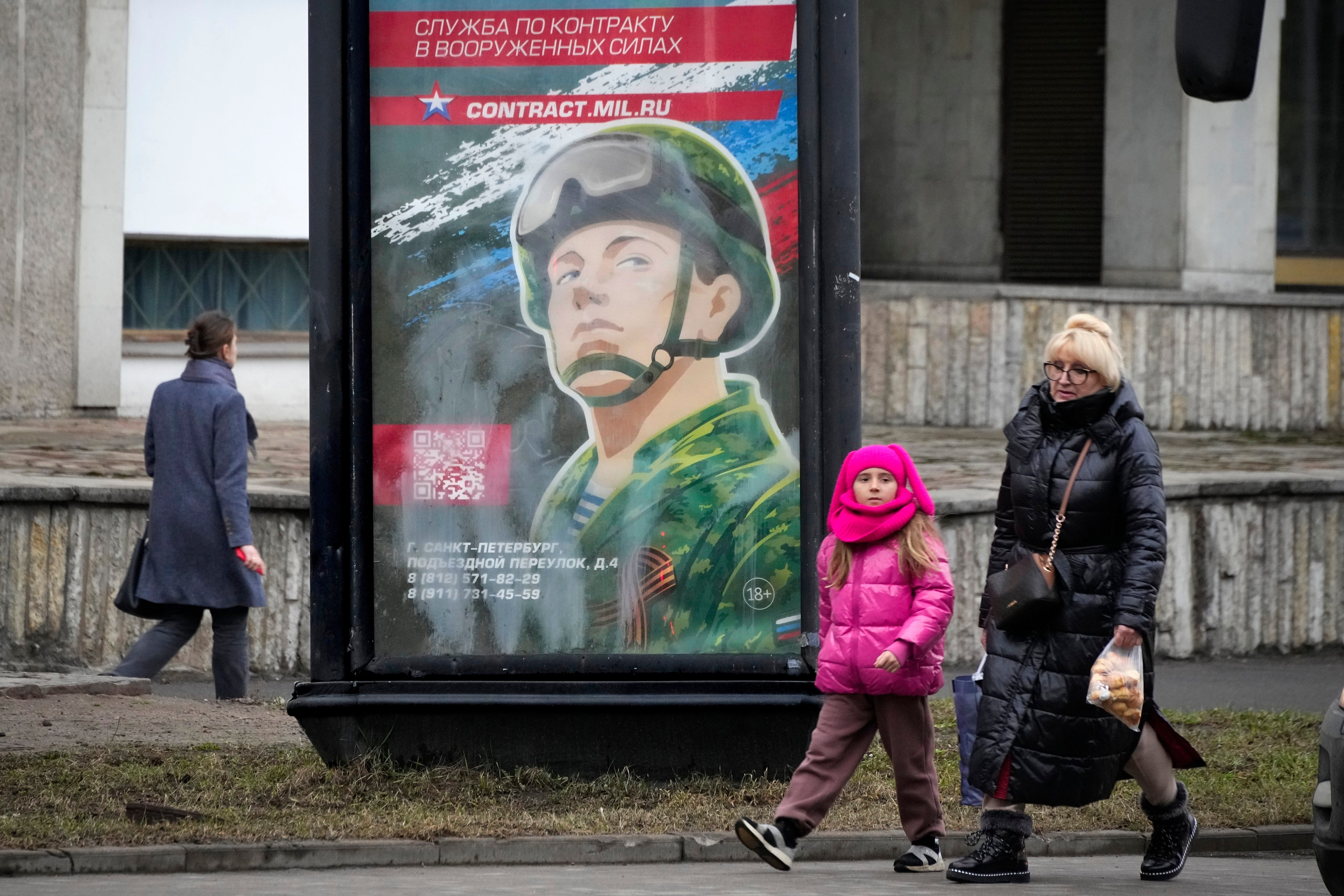 People walk past an army recruiting billboard with the words 