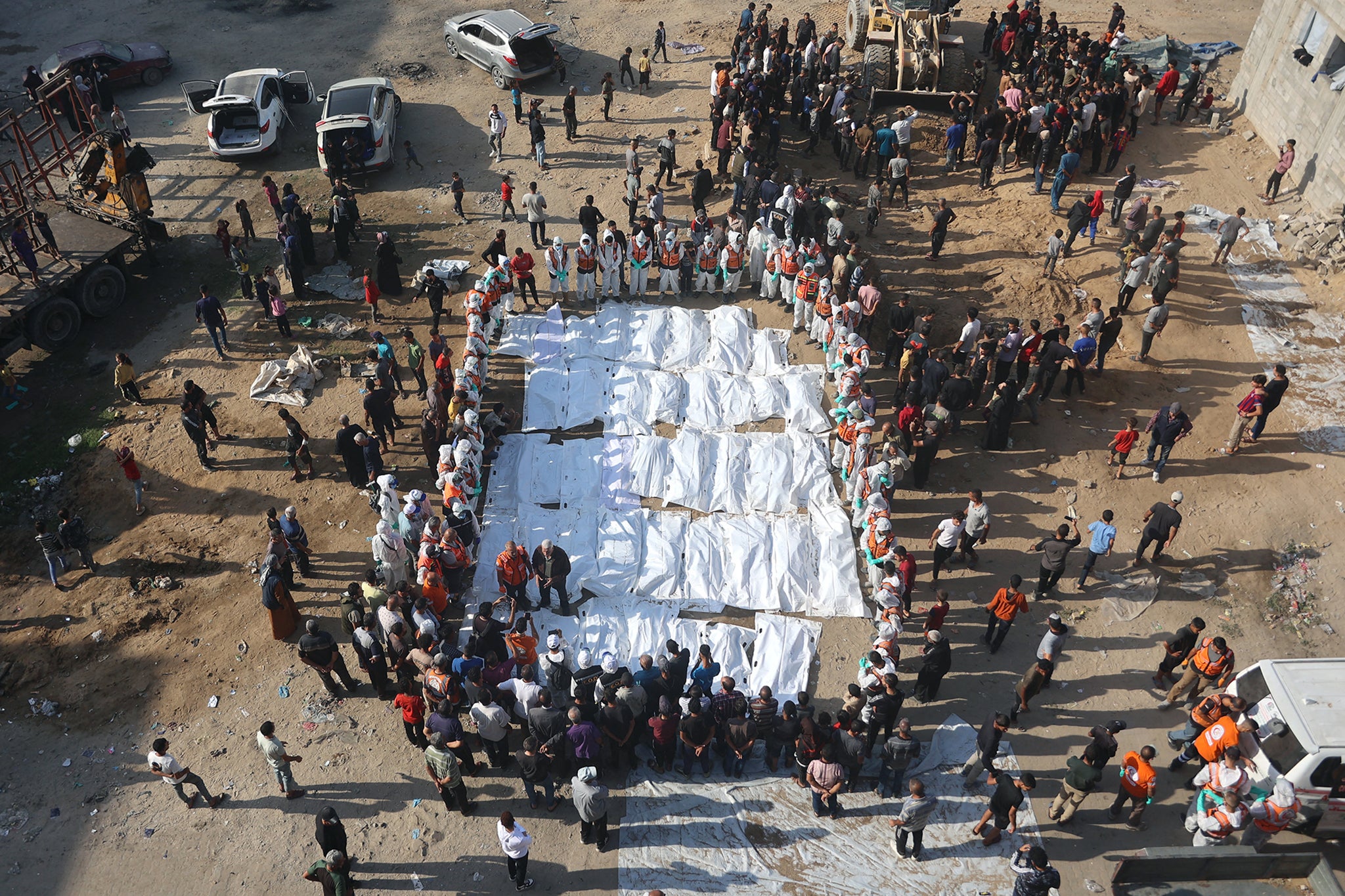 Civil Defense members, in cooperation with the Palestinian Shahebar family, lay out body bags containing the remains of members of the Shahebar family