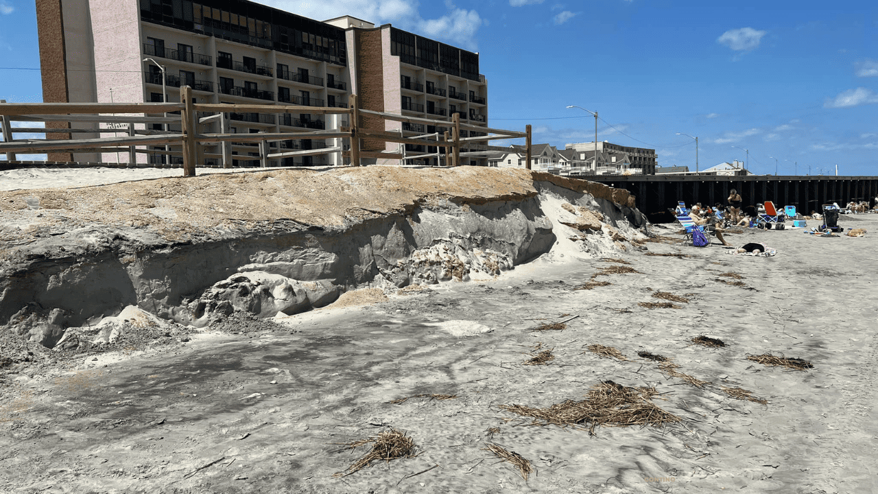 Eroded rock formation near industrial buildings under a clear sky.