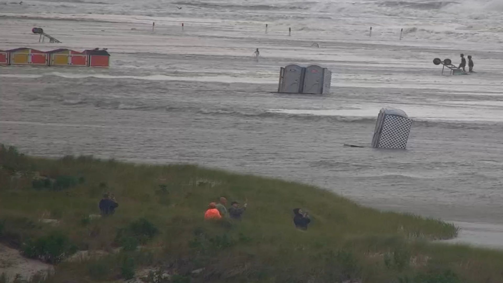 Flooded beach with scattered debris and people.