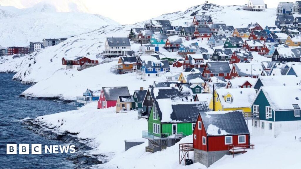 Colourful little houses stand amid lots of snow next to some water