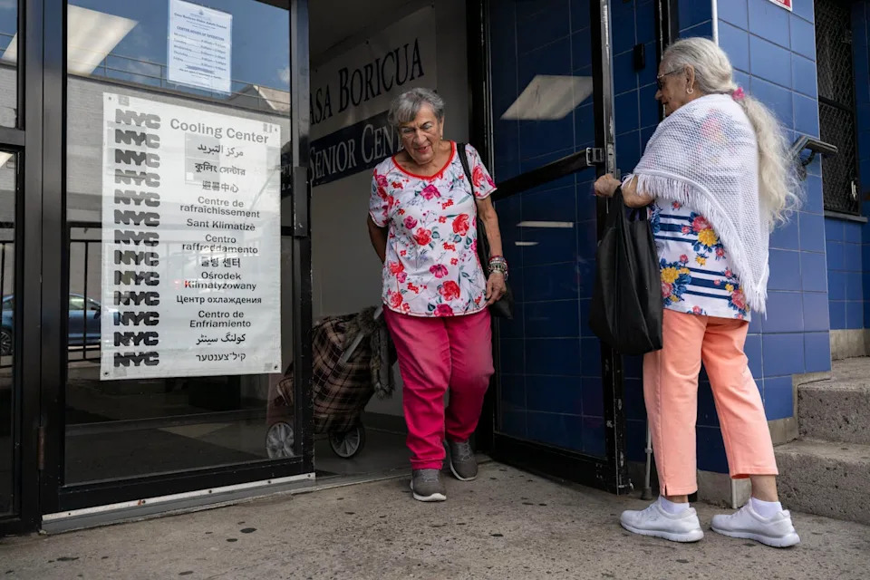 A older man holds a door for a woman at a cooling center.