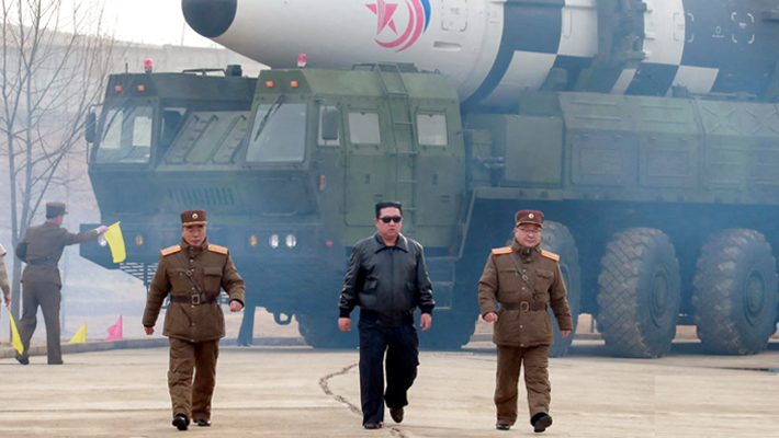 Kim standing before missiles