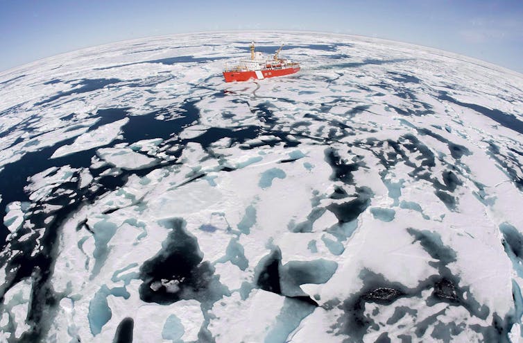 A red boat makes its way through ice-studded water.