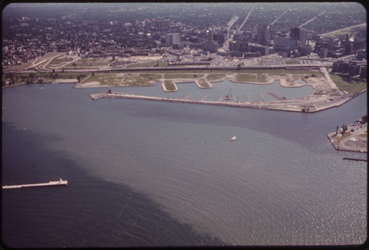 A large stretch of discolored water flows into a larger body of water.
